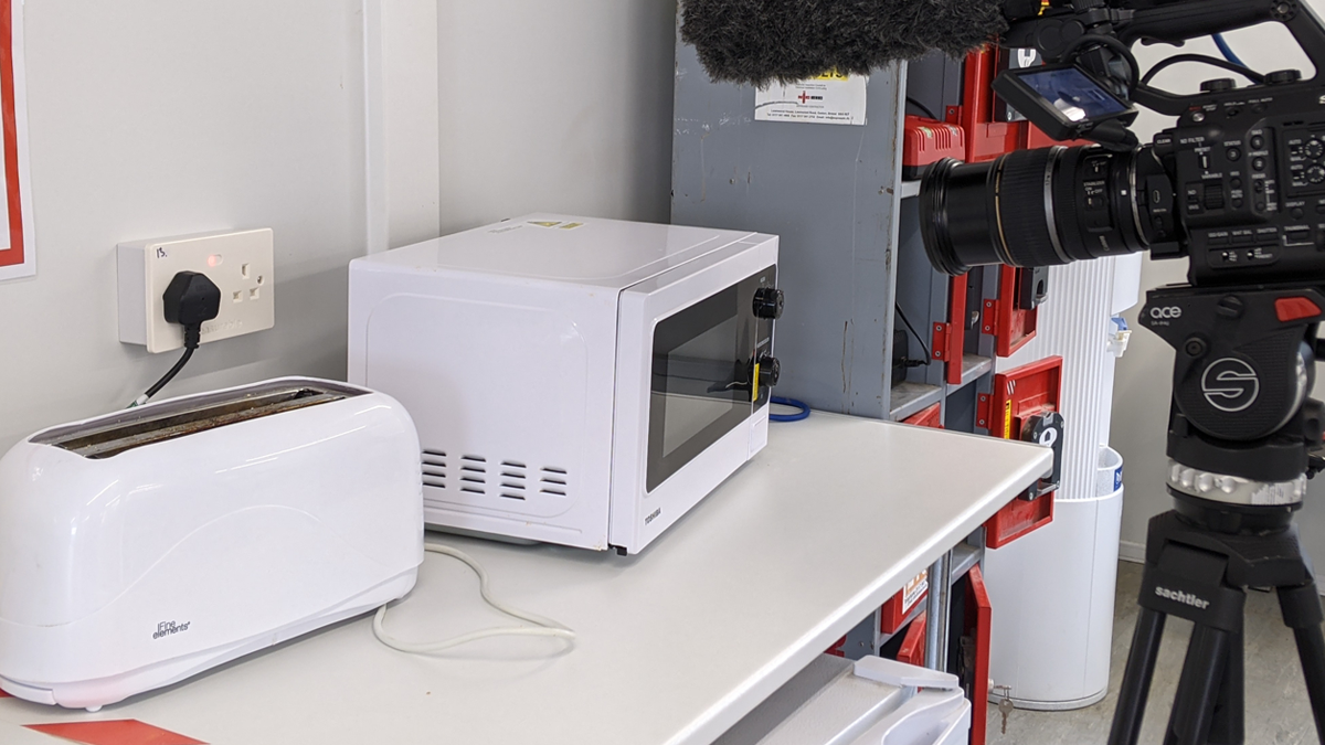 A toaster plugged into a measurable.energy socket, with a microwave and camera to the right.
