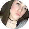 Young woman with long brown hair wearing a black choker necklace, smiling for a professional IT services team photo