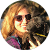 Woman smiling outdoors holding a black dog, wearing sunglasses, representing Red Team IT's friendly Denton TX IT support team