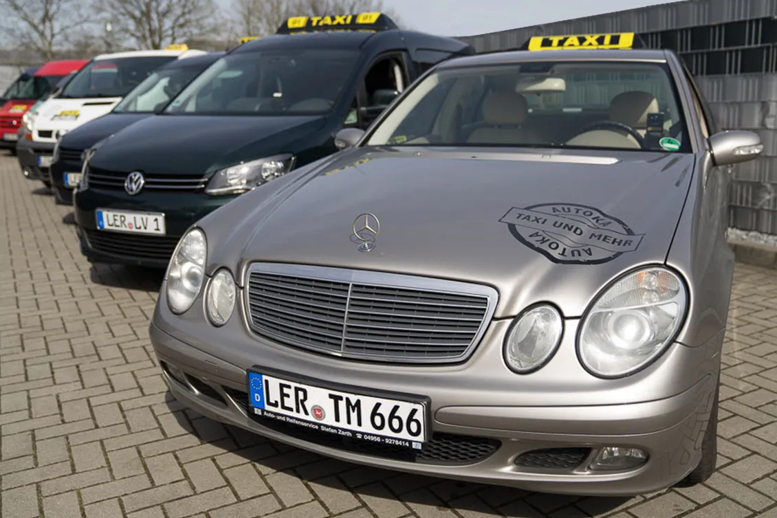 Mehrere Taxis in einer Reihe, im Vordergrund ein silberner Mercedes mit deutschem Kennzeichen und Taxi-Dachzeichen.