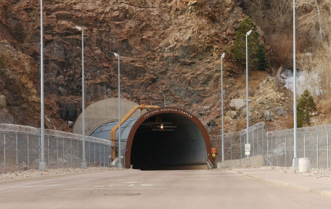 The fortified concrete and steel tunnel entrance to the Cheyenne Mountain nuclear bunker, embedded in a steep granite rock face.