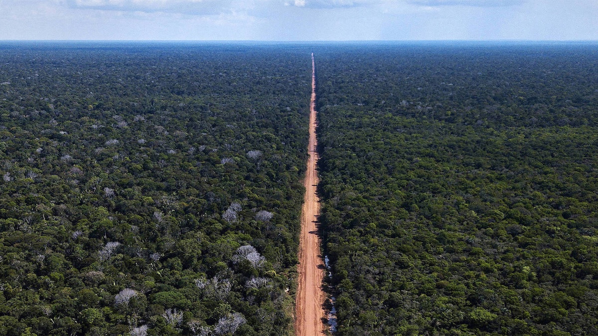 Aerial view of the Trans-Amazonian Highway cutting in a straight line through dense rainforest in Brazil.