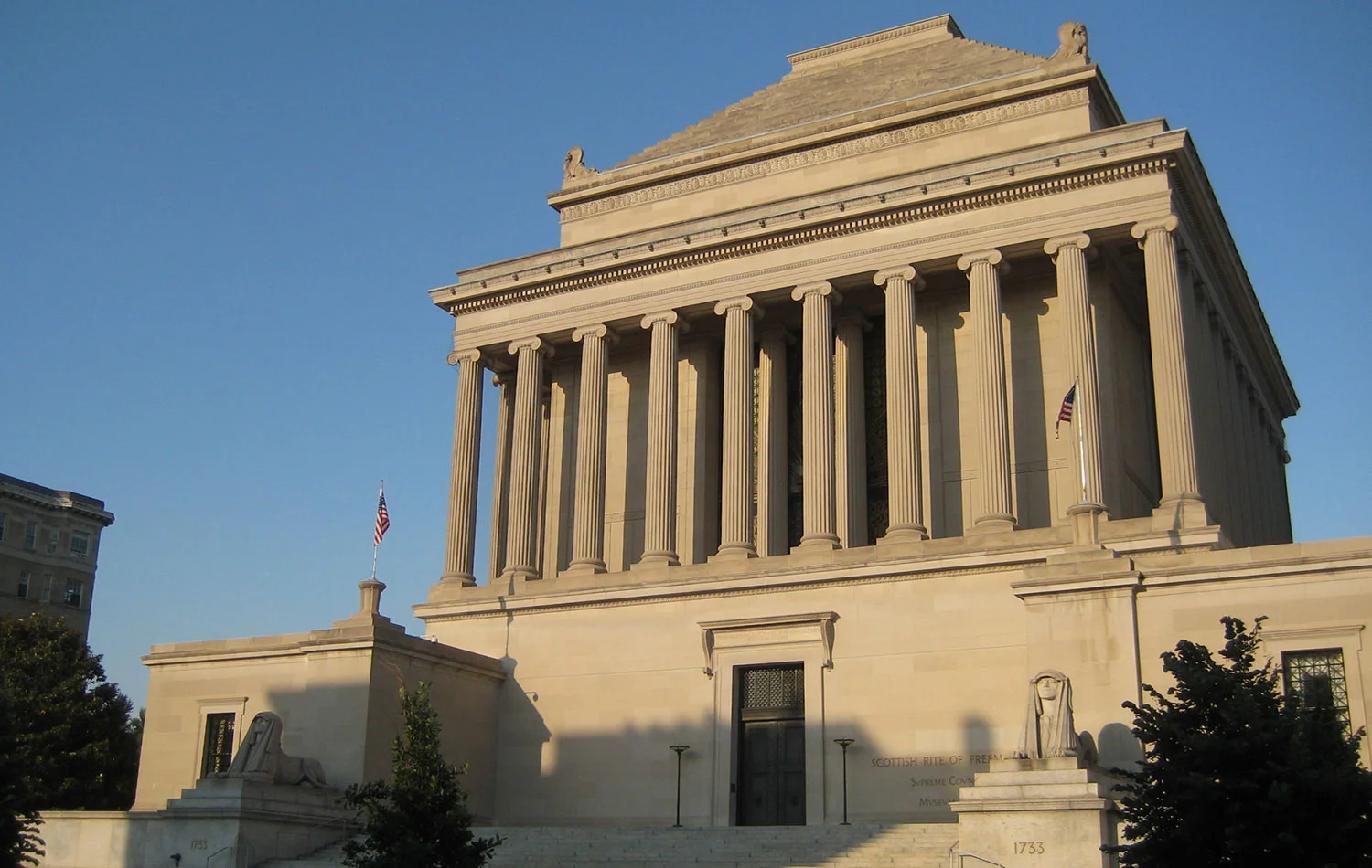 Exterior view of the House of the Temple in Washington, D.C., a monumental neoclassical Masonic building with tall columns, stone steps, and American flags.