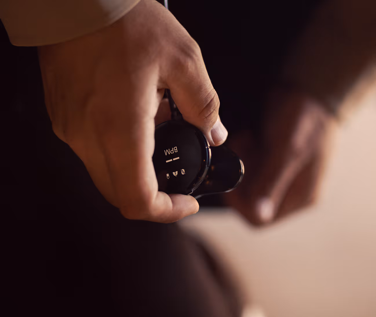 Close-up of a hand holding a digital stethoscope displaying "BPM" and heart rate icons.