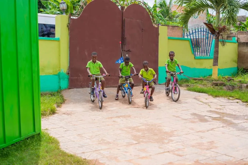 Vier Kinder fahren mit gespendeten Fahrrädern im Hof der Joy Stars School in Ghana