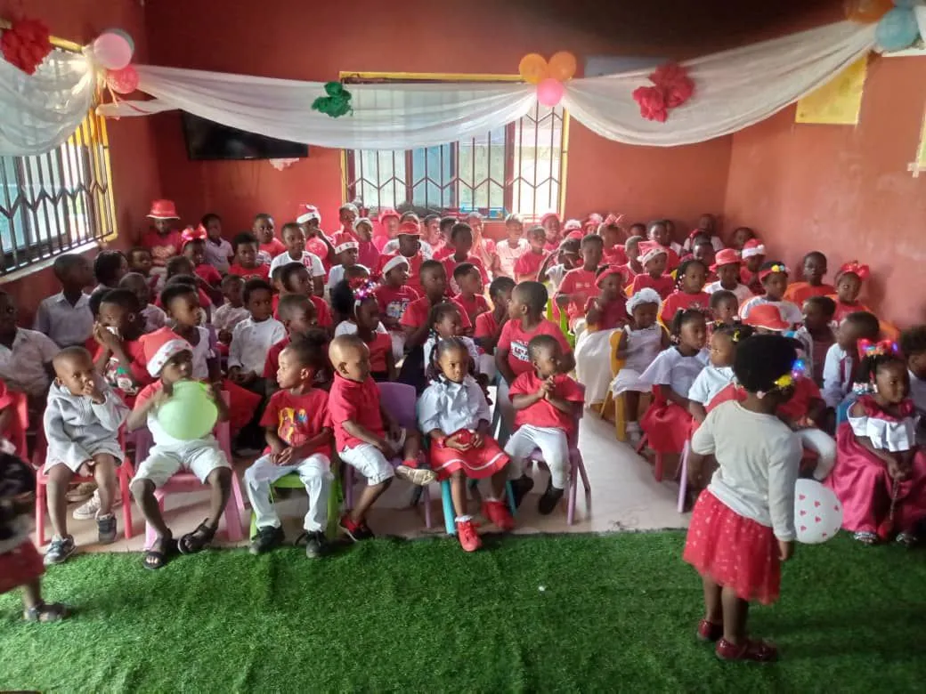 Viele Kinder in roten und weißen Kleidern feiern eine Weihnachtsfeier in der Joy Stars School in Ghana