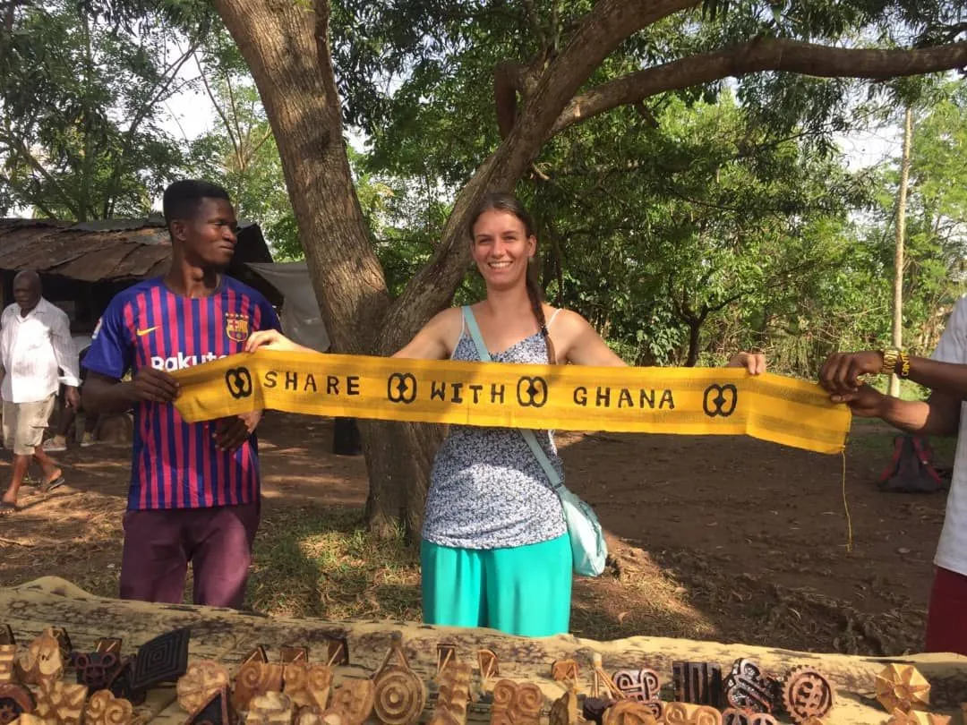 Katharina hält ein gelbes Banner mit der Aufschrift Share with Ghana
