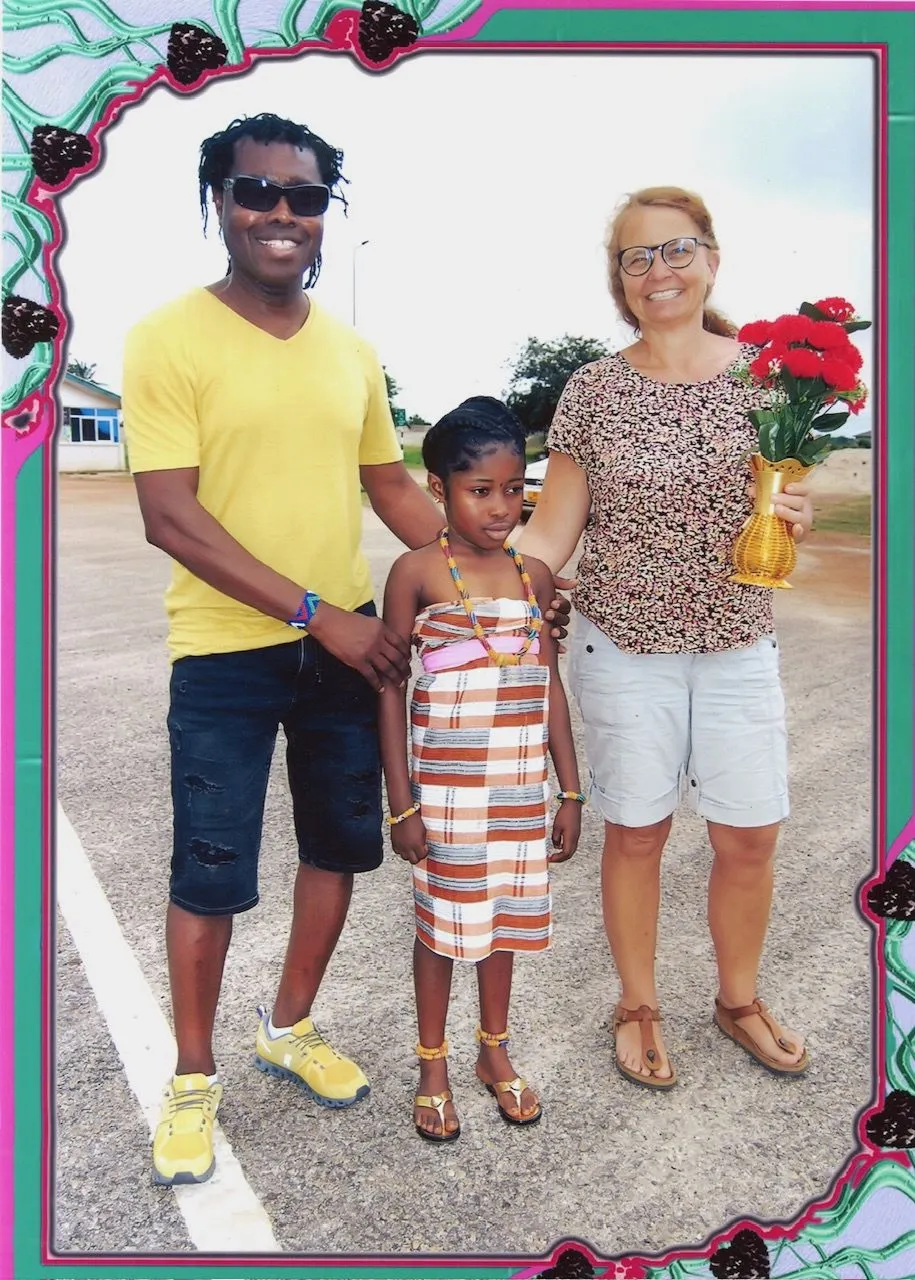 Ansu und Andrea mit einem Mädchen in traditioneller Kleidung und Blumenstrauß in Ghana