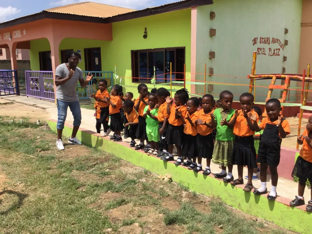 Kinder klatschen vor der Schule, Ansu motiviert sie