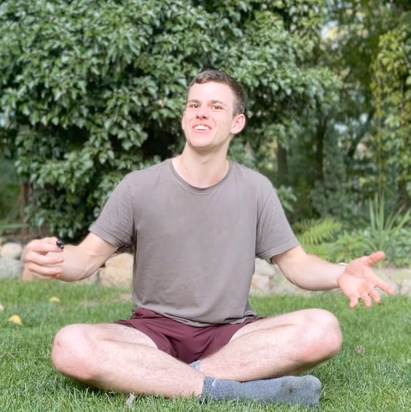 Mitglied sitzt im Schneidersitz auf der Wiese und gibt ein Interview.