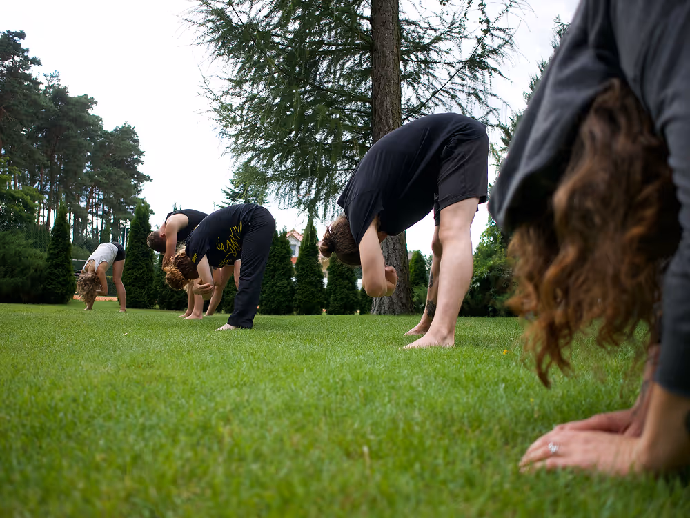 Teilnehmer:innen beim Warm-up auf der Wiese beim Movement Camp in Polen