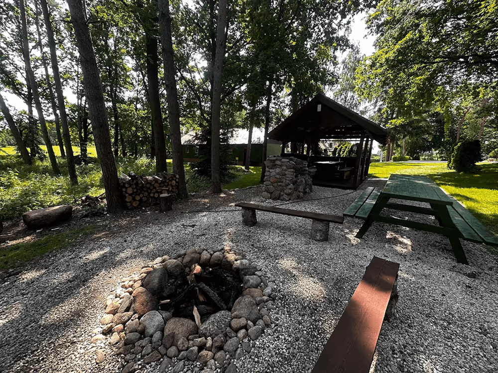 Feuerstelle mit Sitzbänken und Pavillon im Garten der Movement Camp Location