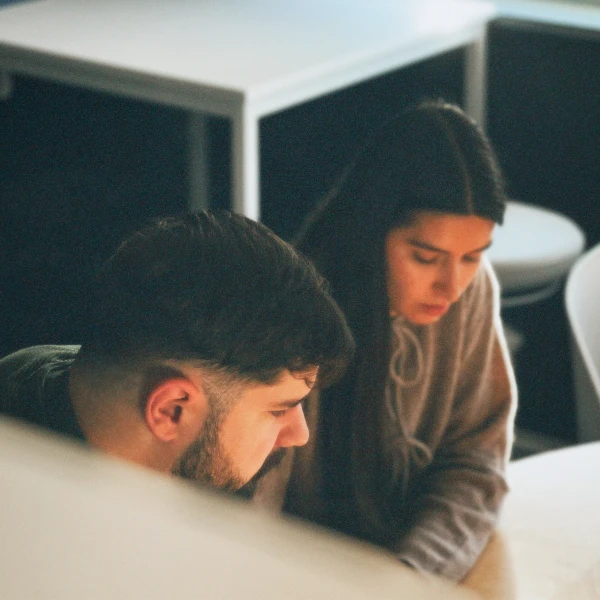 Two people, a man and a woman, sitting closely together at a table, both focused on something in front of them.
