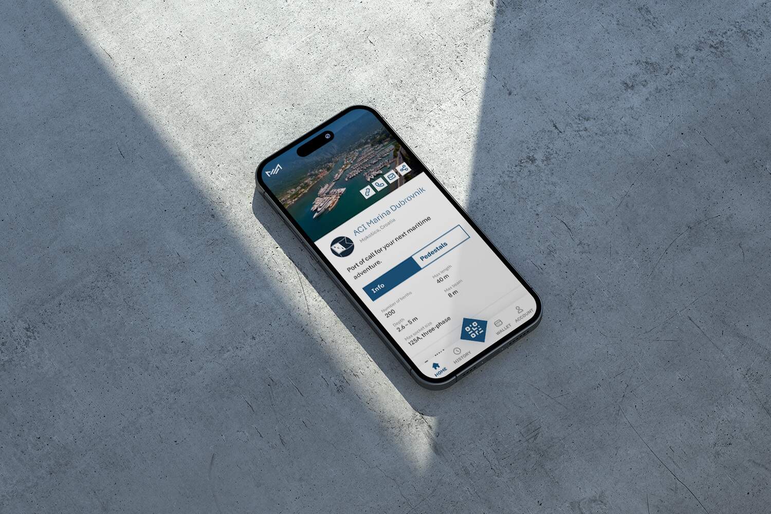 An iPhone lying on a grey concrete surface shows the Marex.es marina management app interface with business metrics.