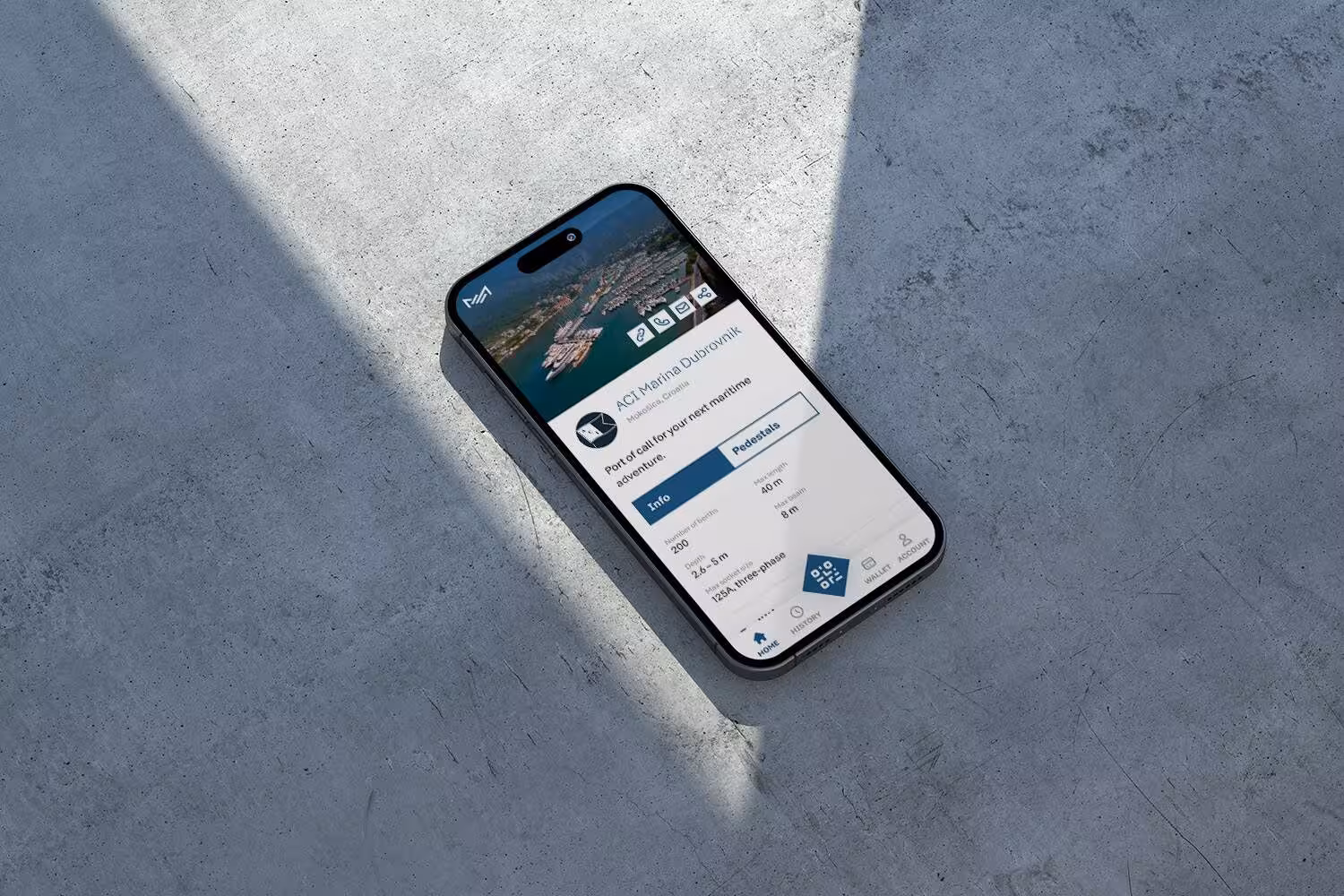 An iPhone lying on a grey concrete surface shows the Marex.es marina management app interface with business metrics.