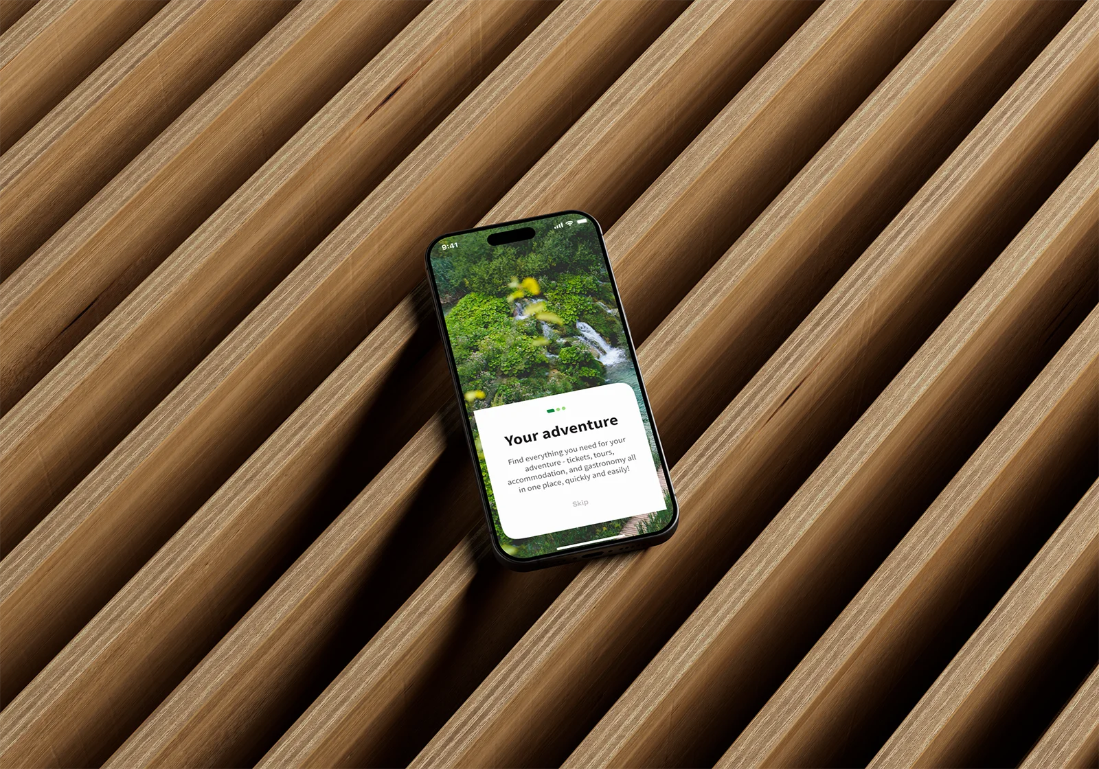 An iPhone resting on wooden slats displays the Plitvice Lakes National Park mobile app welcome screen featuring a nature photo.