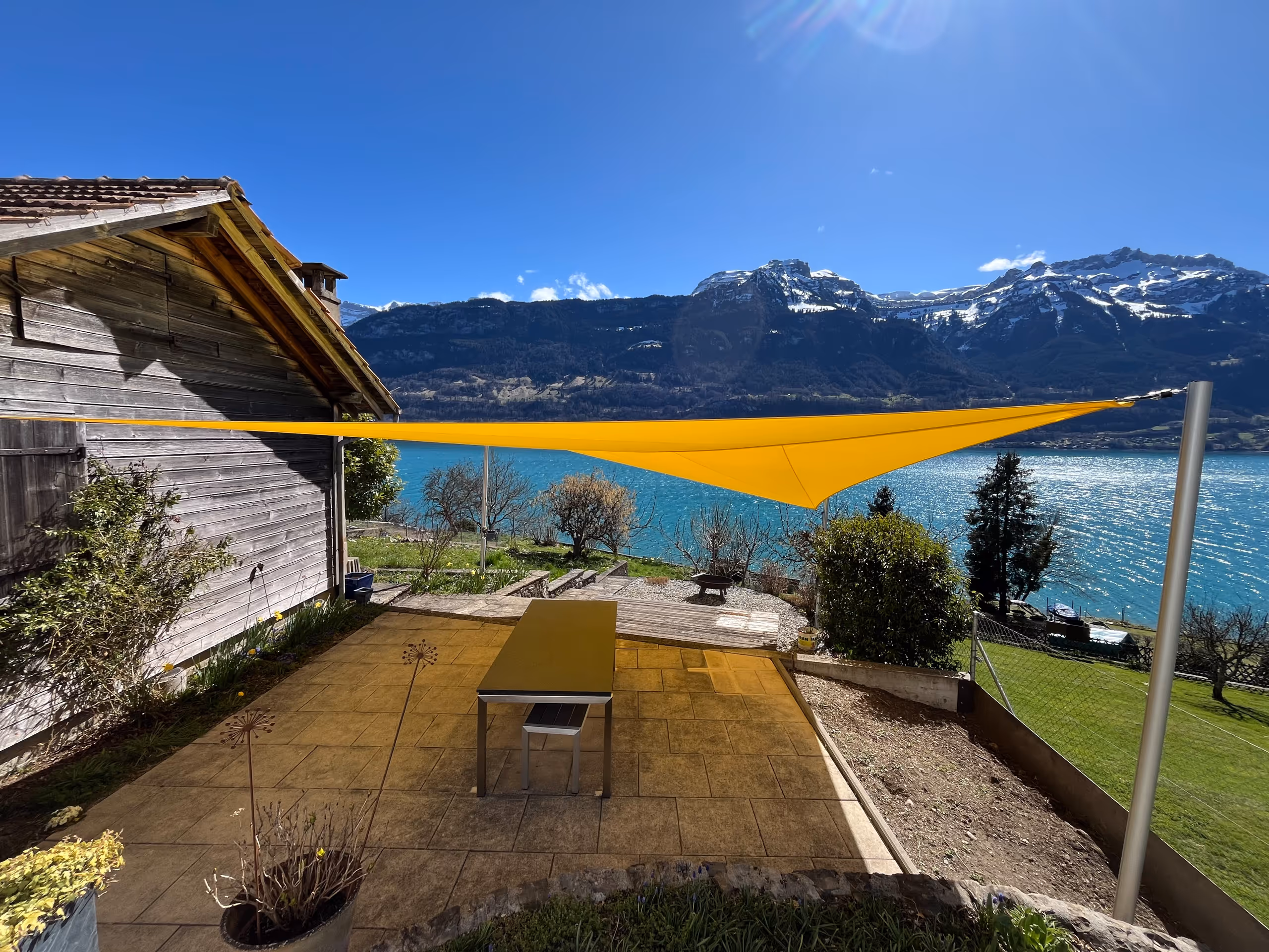 Gelbes Sonnensegel über einer Terrasse mit Seeblick und Bergpanorama