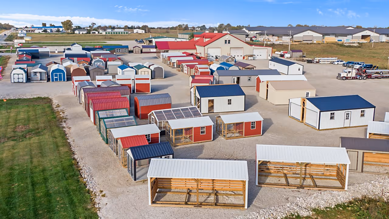 Outdoor lot displaying various sheds and small storage buildings of different colors and styles under a clear sky.