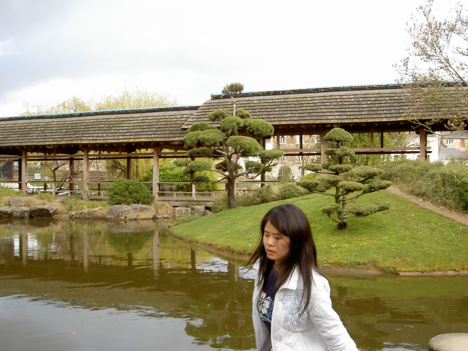 Yun Cao, certified QHHT® hypnotherapist level 2 from Hype’notic Studio, standing by a peaceful Japanese garden pond in Vancouver.