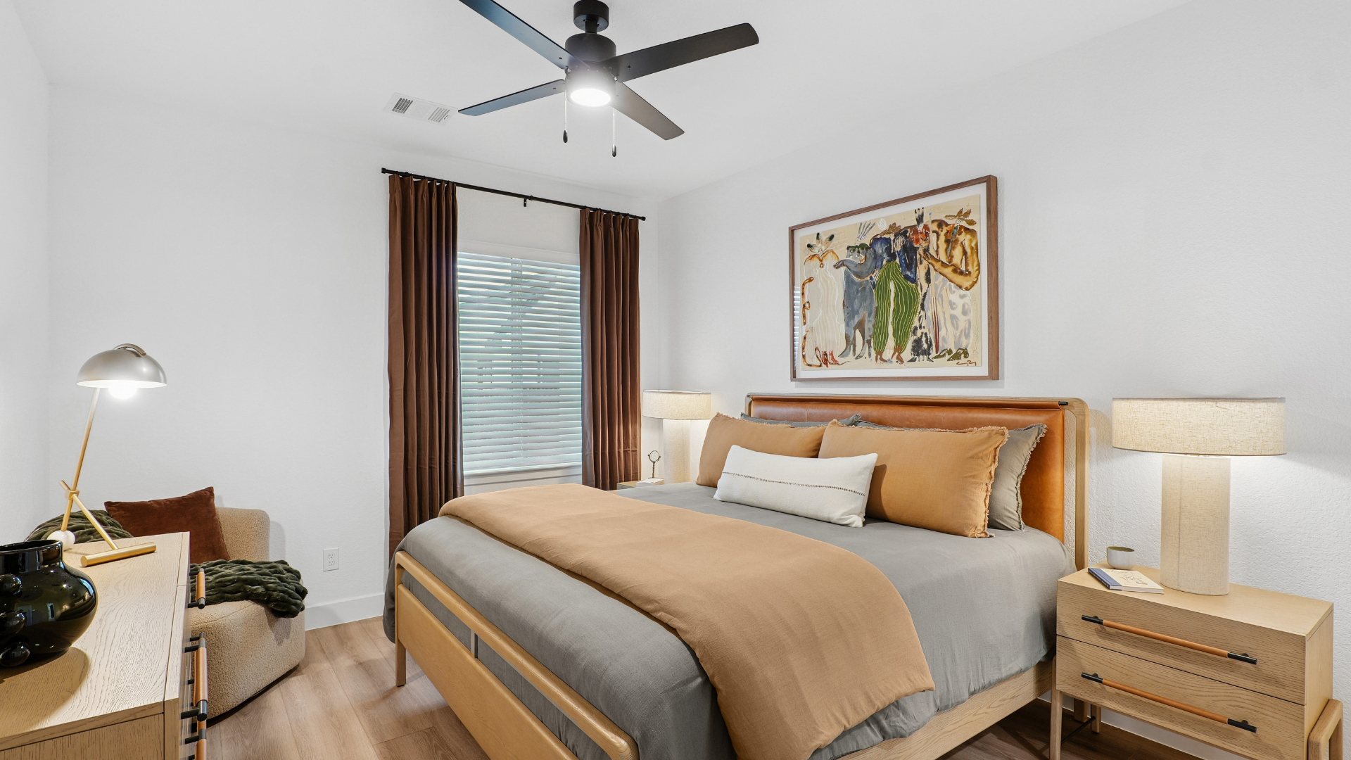 Apartment dining and living area with a modern gray accent wall, a ceiling fan, and an open view to the kitchen with gray cabinets in Humble, TX.