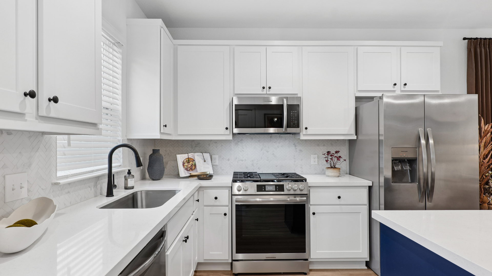 Apartment dining and living area with a modern gray accent wall, a ceiling fan, and an open view to the kitchen with gray cabinets in Humble, TX.