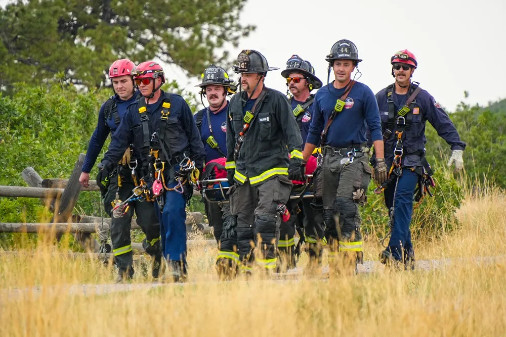 Group of firefighters in helmets and harnesses walking together during rope rescue training
