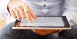 A man sitting down holding a tablet computer.