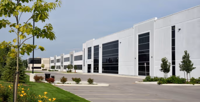 A large building with a lot of windows and a parking lot.