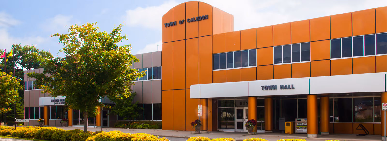 A large orange building with a tree in front of it.
