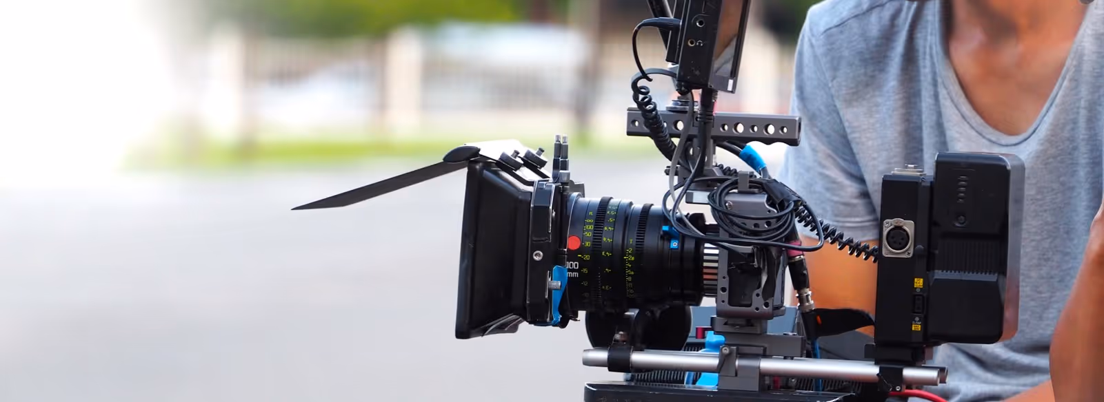 A man standing next to a camera on a tripod.