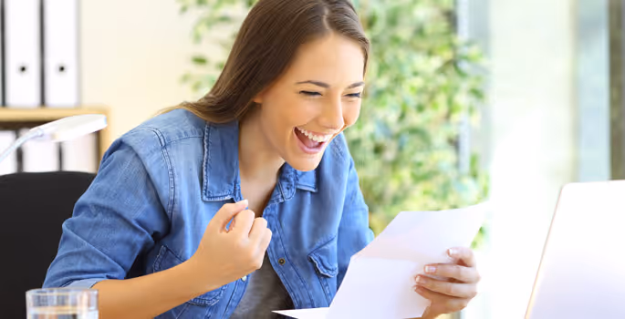 A woman laughing while looking at a piece of paper.