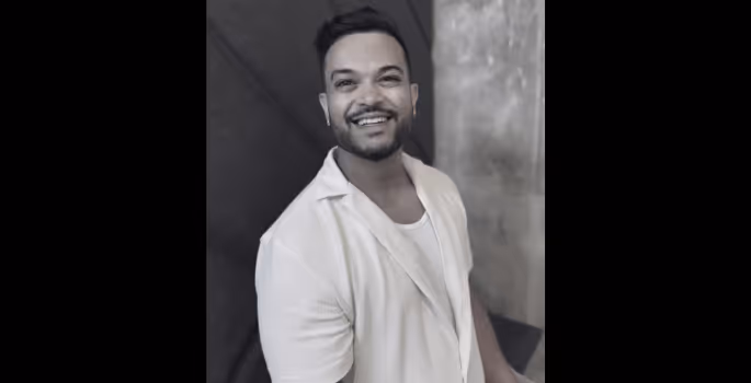 A man in a white shirt is smiling.