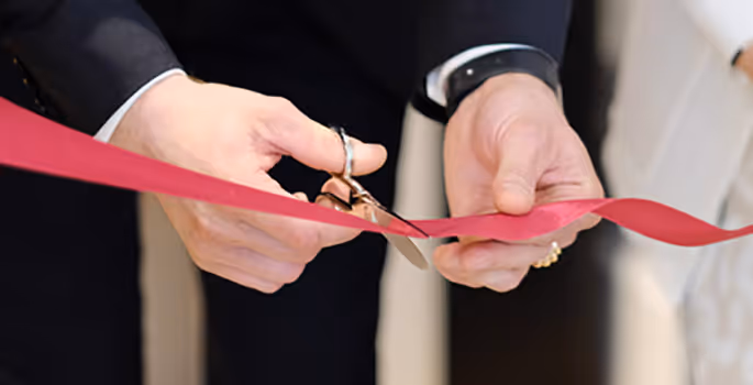 A man and woman cutting a red ribbon.