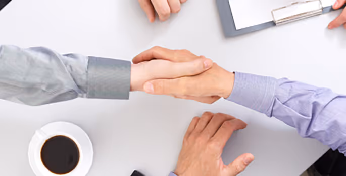 A group of people shaking hands over a table.