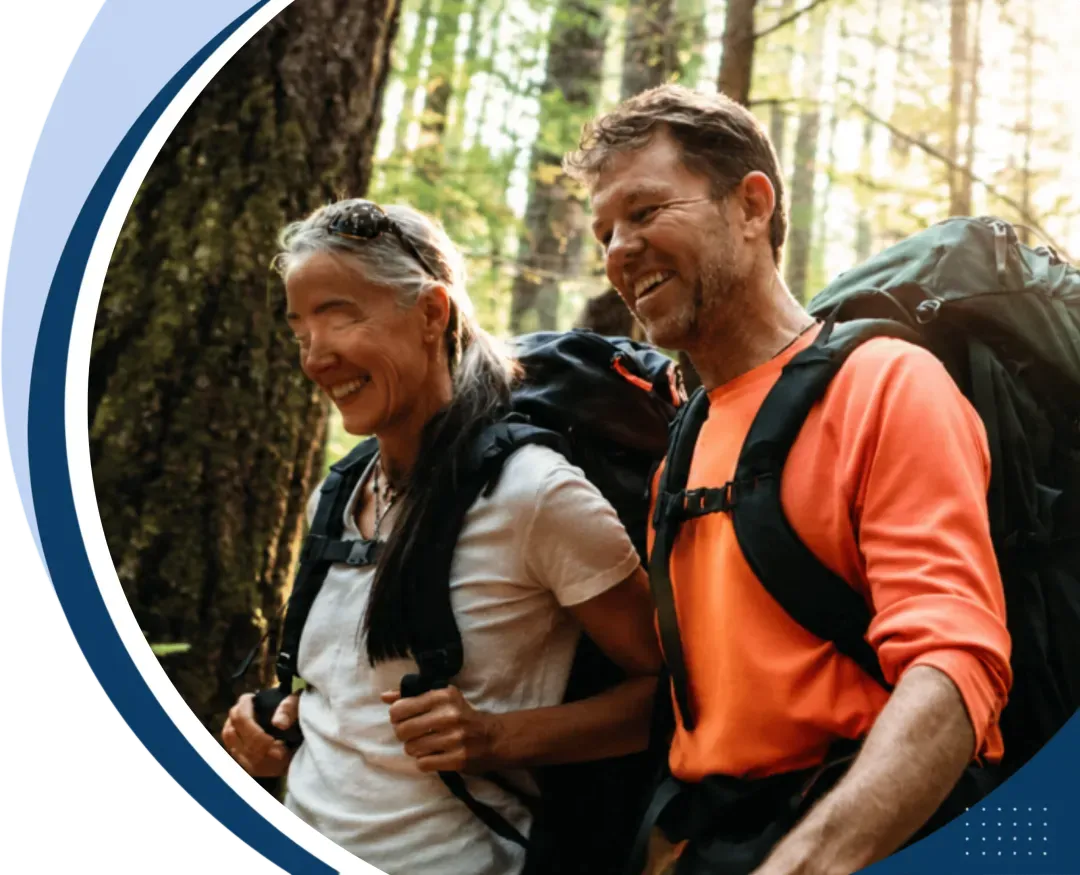 Smiling mature couple backpacking through a forest