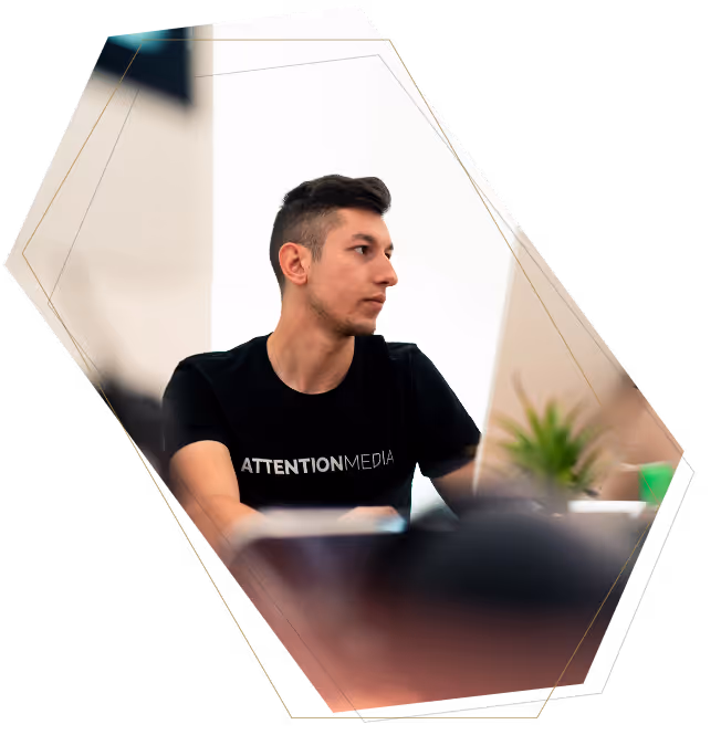 Young man wearing a black Attention Media t-shirt sitting and looking to the side in a bright room.