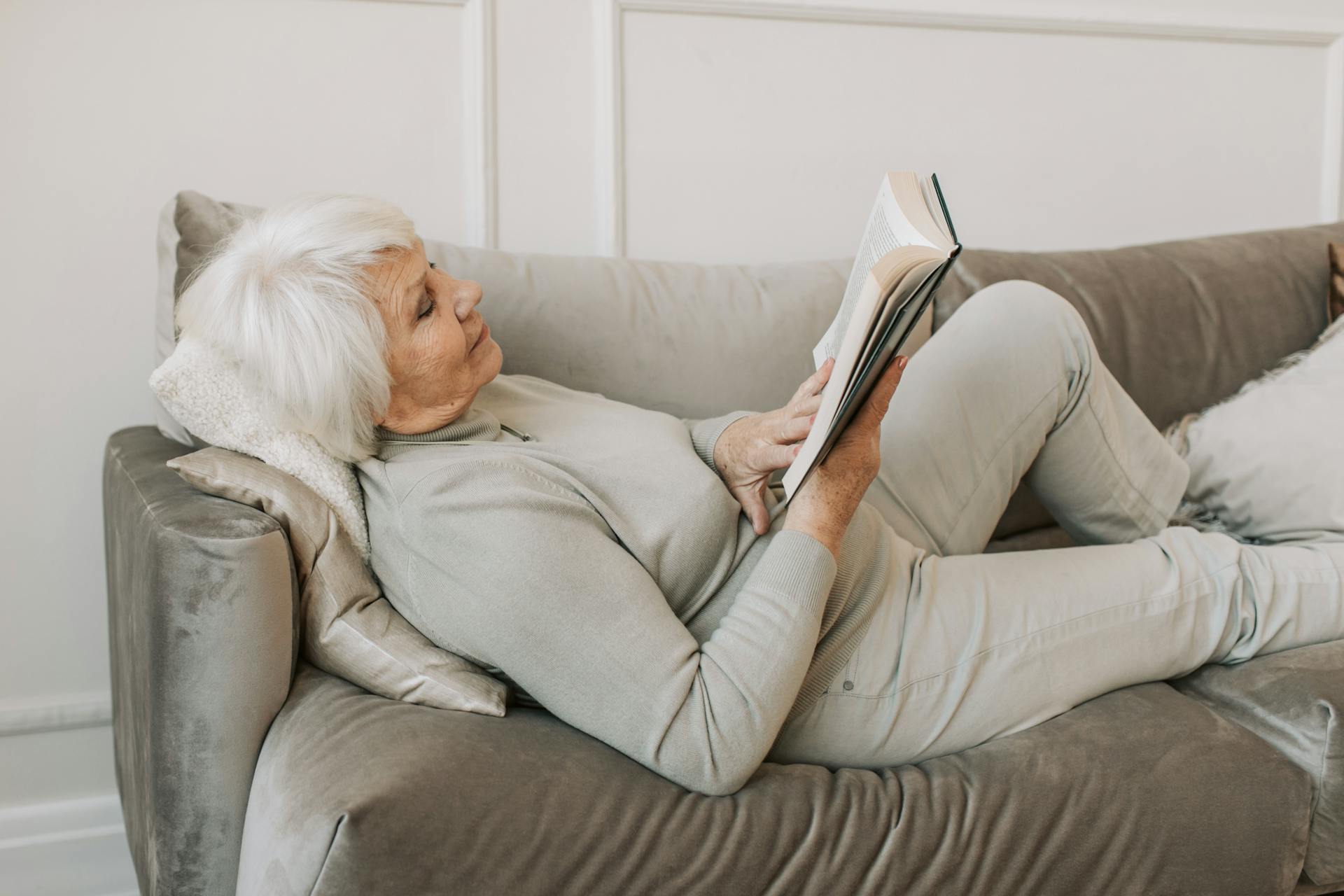 Grand mother lying on a couch while reading a book