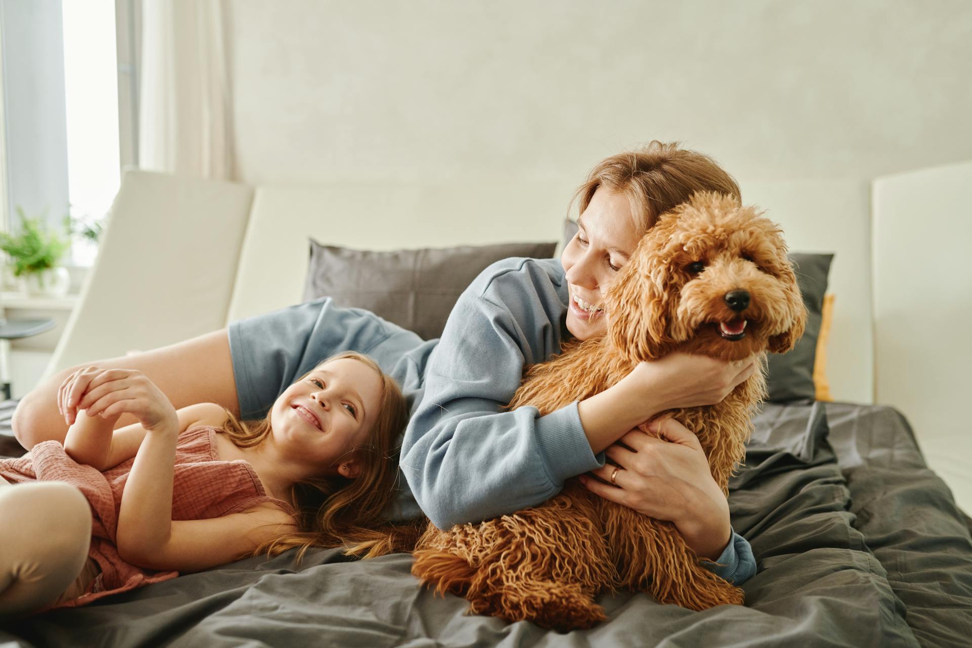 Mother hugging a dog with her daughter lying and looking at her