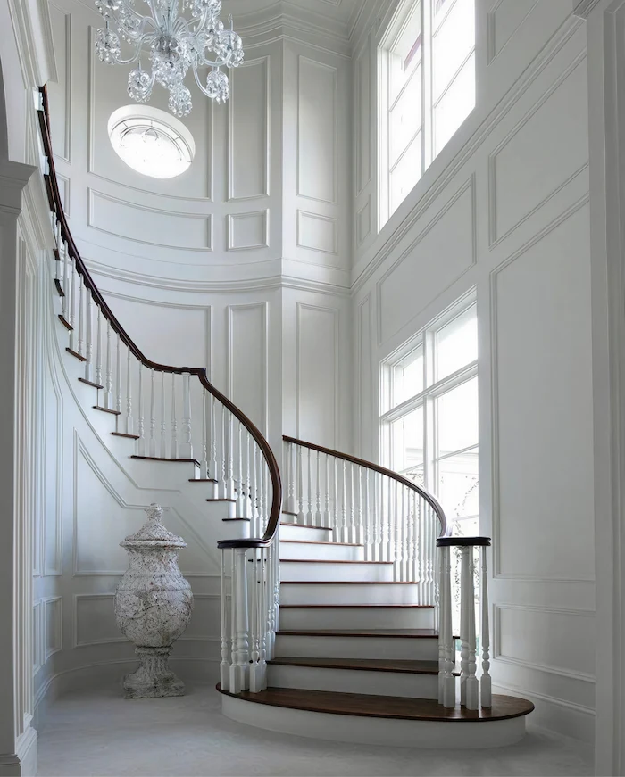 A French Provincial style grand staircase, featuring an ornate vessel and chandelier