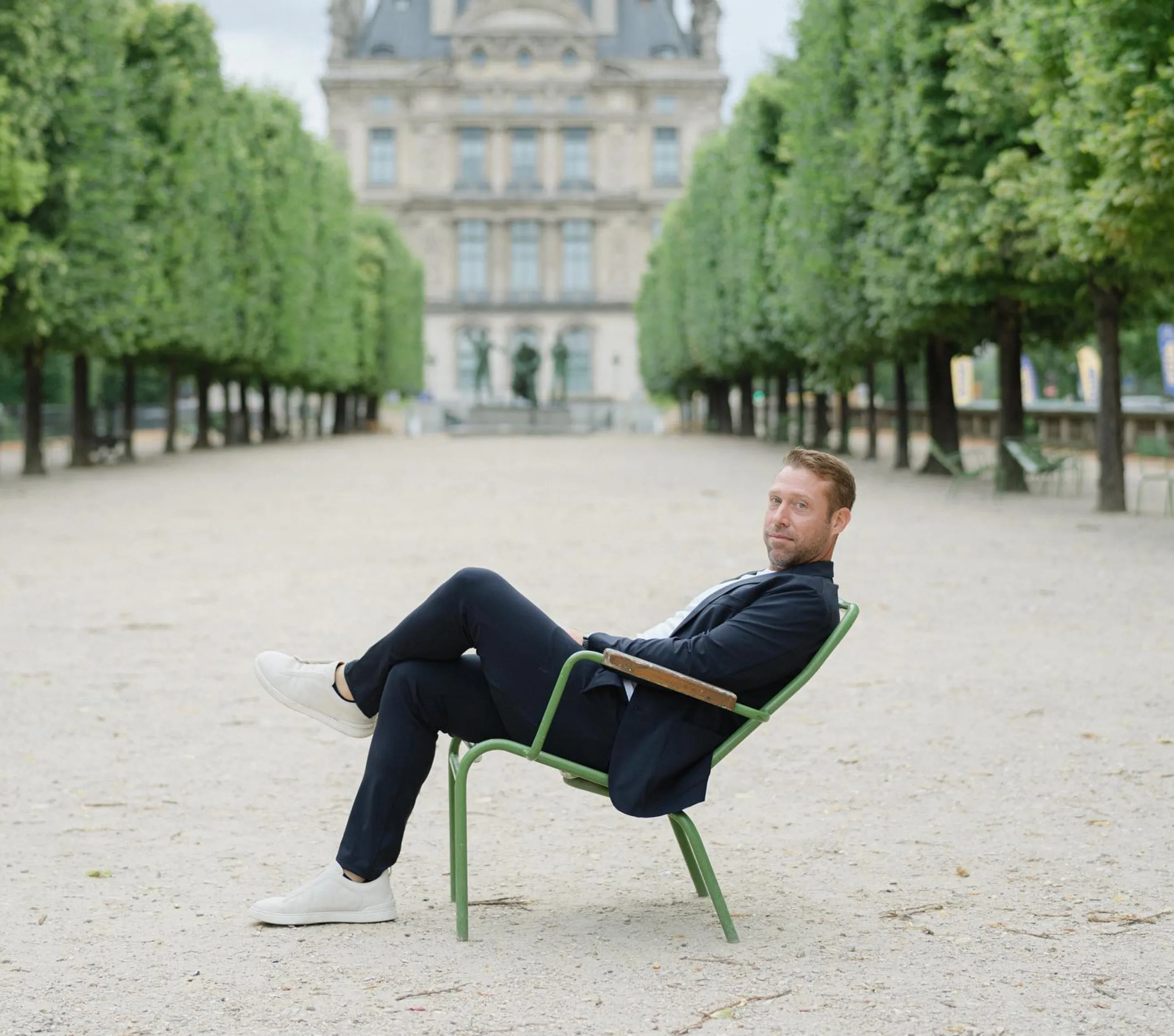 Nick Reinhart seated in a garden chair in a tree-lined courtyard