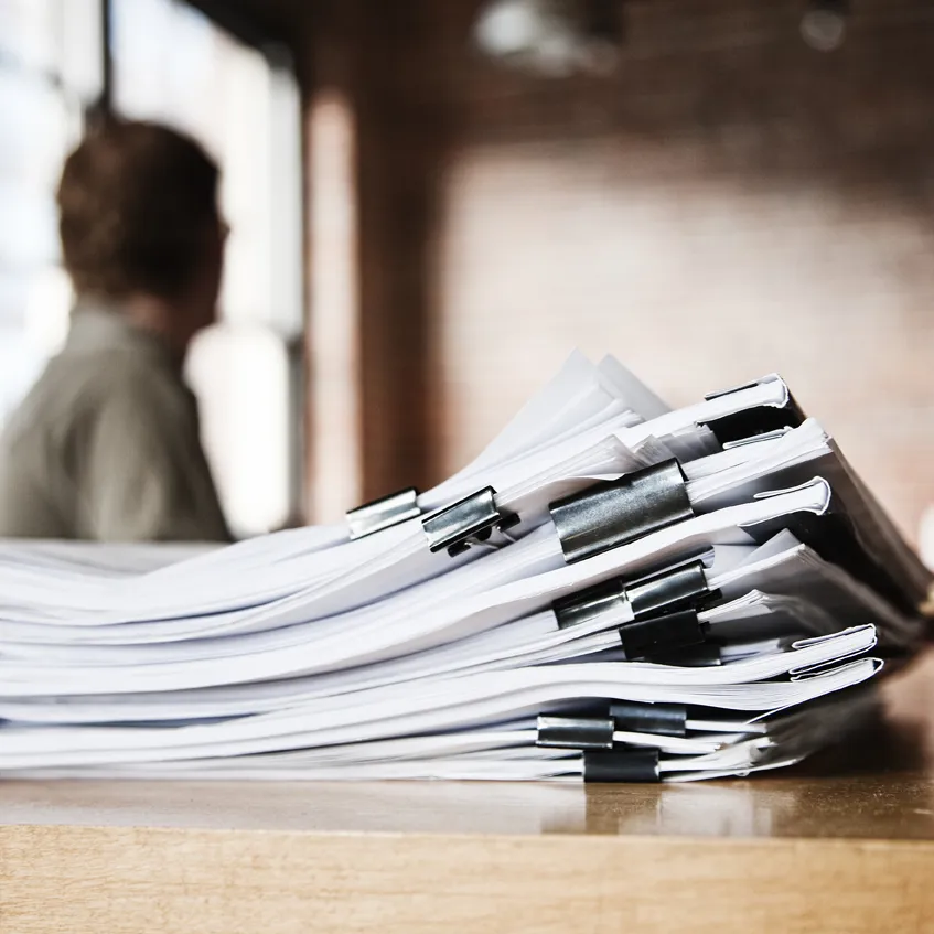 A stack of paperwork on a desk.