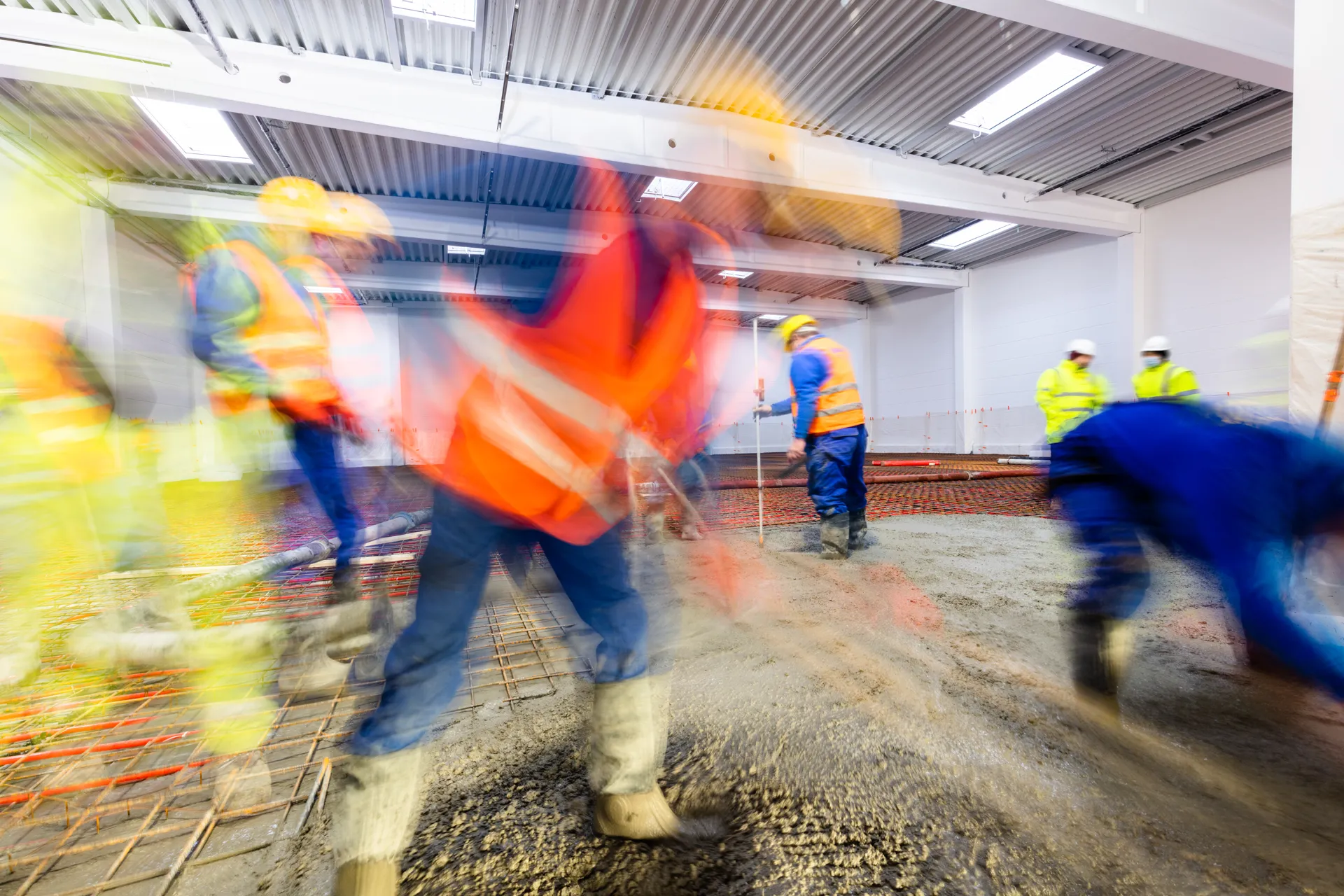 A motion-blurred image of a group of consutrction workers at work, all wearing hi-vis.