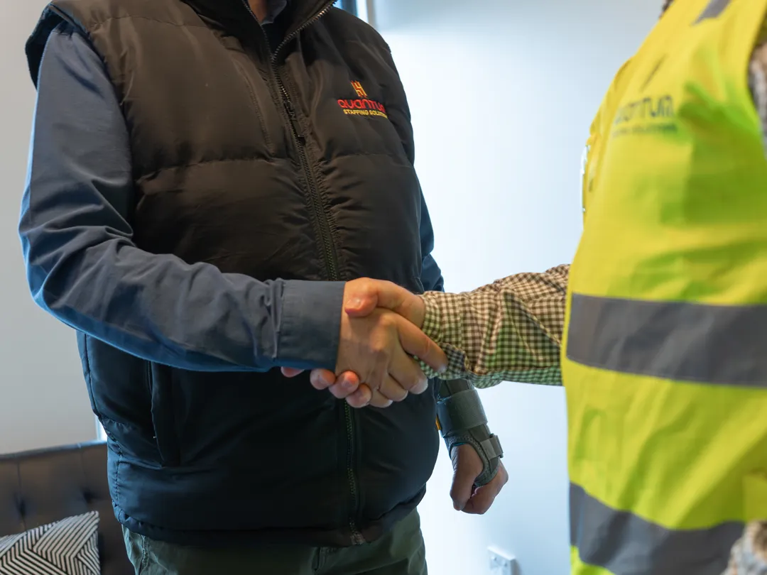 Two people handshaking while wearing Quantum Staffing Solutions branded apparel.