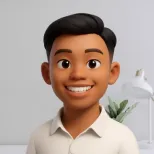 Smiling young man with neatly styled dark hair wearing a white collared shirt, standing indoors with a plant in the background.