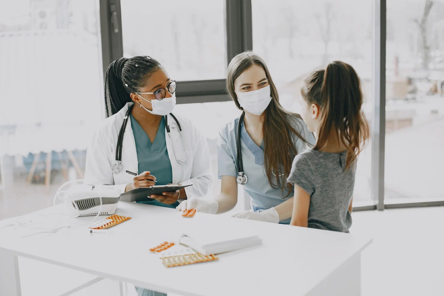 Two clinicians meeting with a child patient in a pediatric primary care office
