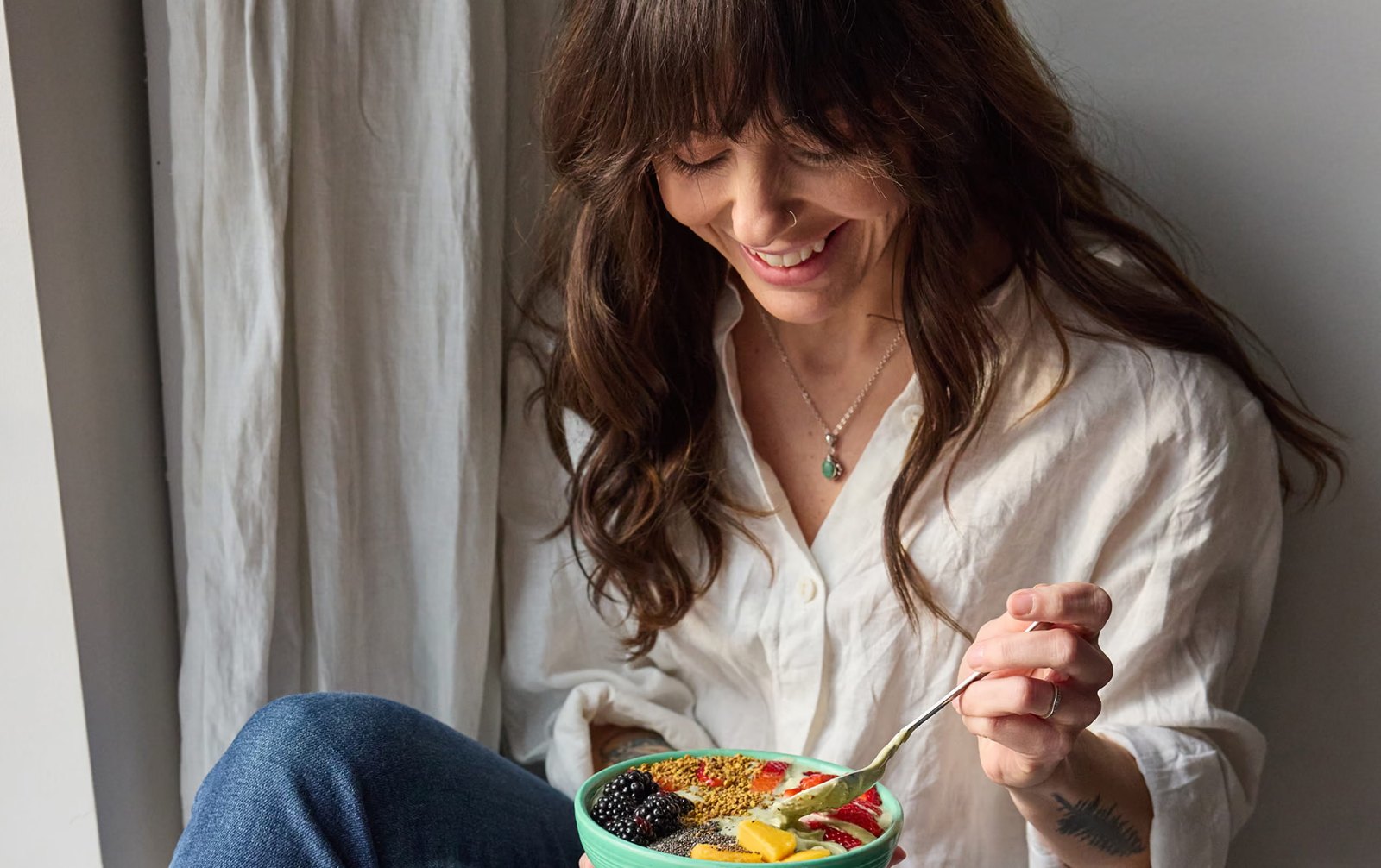 A woman eating a healthy bowl of food, from Nourish, a telehealth nutrition company