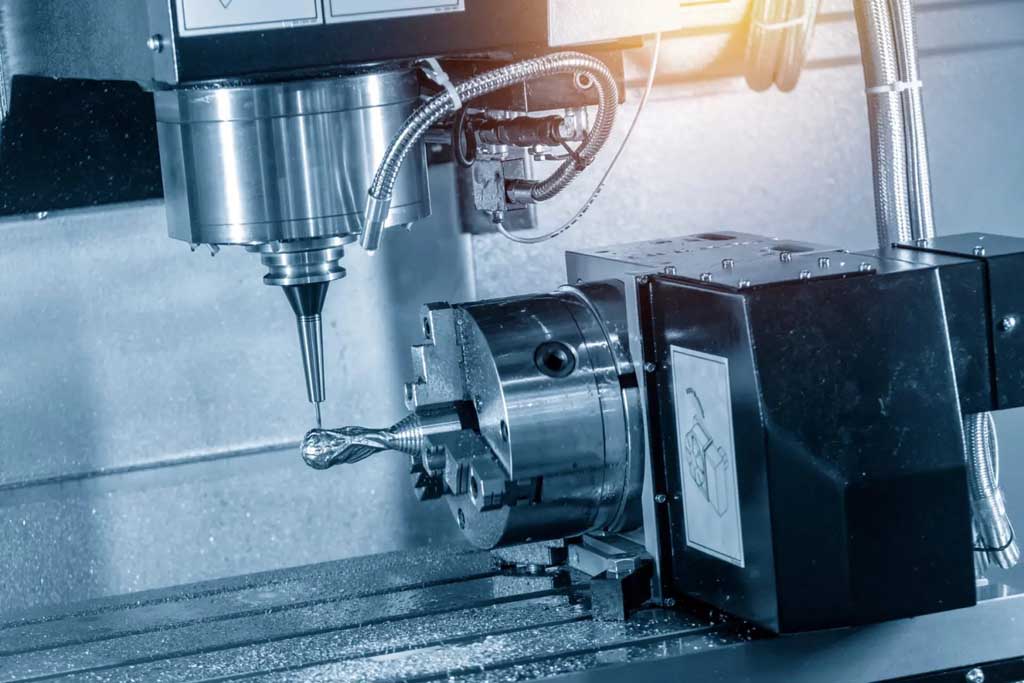 Close-up of a CNC milling machine with a rotating drill bit and metal workpiece mounted on a chuck.