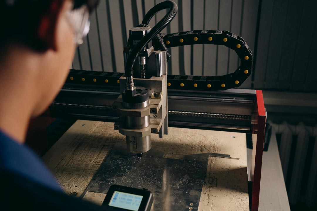 Close-up of a person operating a CNC milling machine cutting a metal sheet.