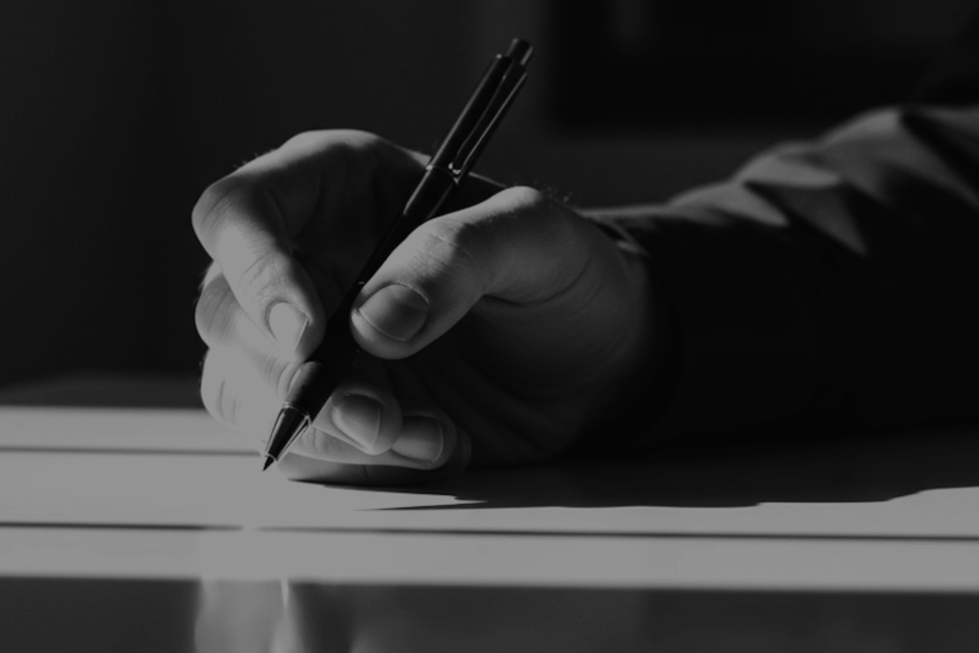 A black and white close up photo of a hand holding a pen