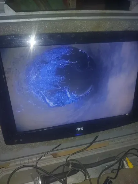 A QFX monitor displaying an image of a dark, circular underwater scene with blue coral or plant life.